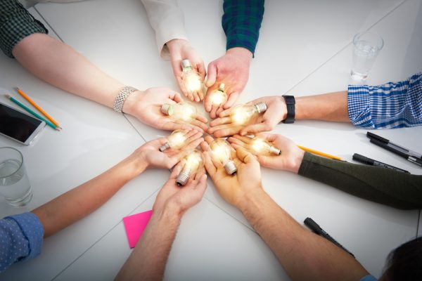 Teamwork and brainstorming concept with businessmen that share an idea with a lamp. Concept company startup